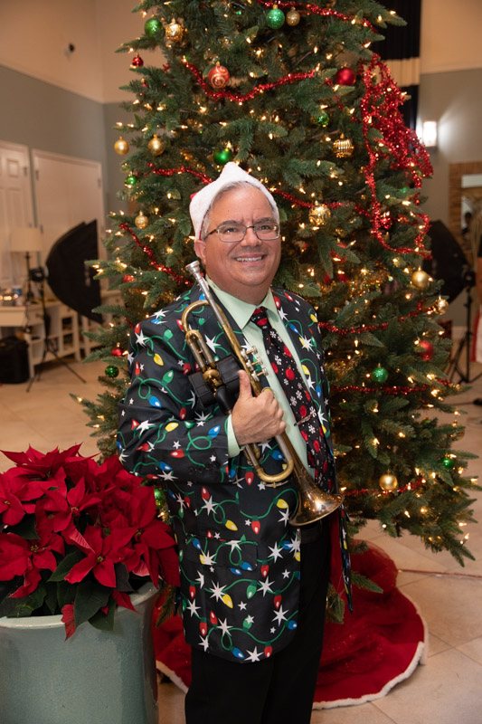 In a Christmas jacket beside a decorated tree