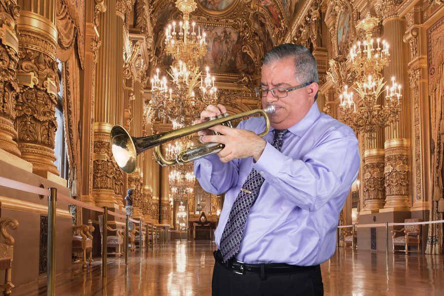 Playing trumpet in an ornate hall beneath chandeliers