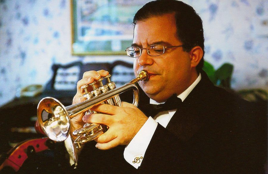 Allen J. Venezio playing trumpet in a tuxedo