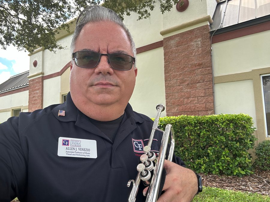 Allen J. Venezio outdoors with trumpet and sunglasses